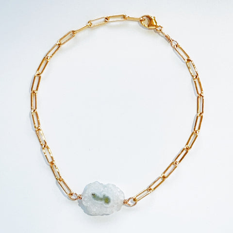 Flat lay photo of 14 kt gold fill paperclip chain bracelet featuring white solar quartz slice.