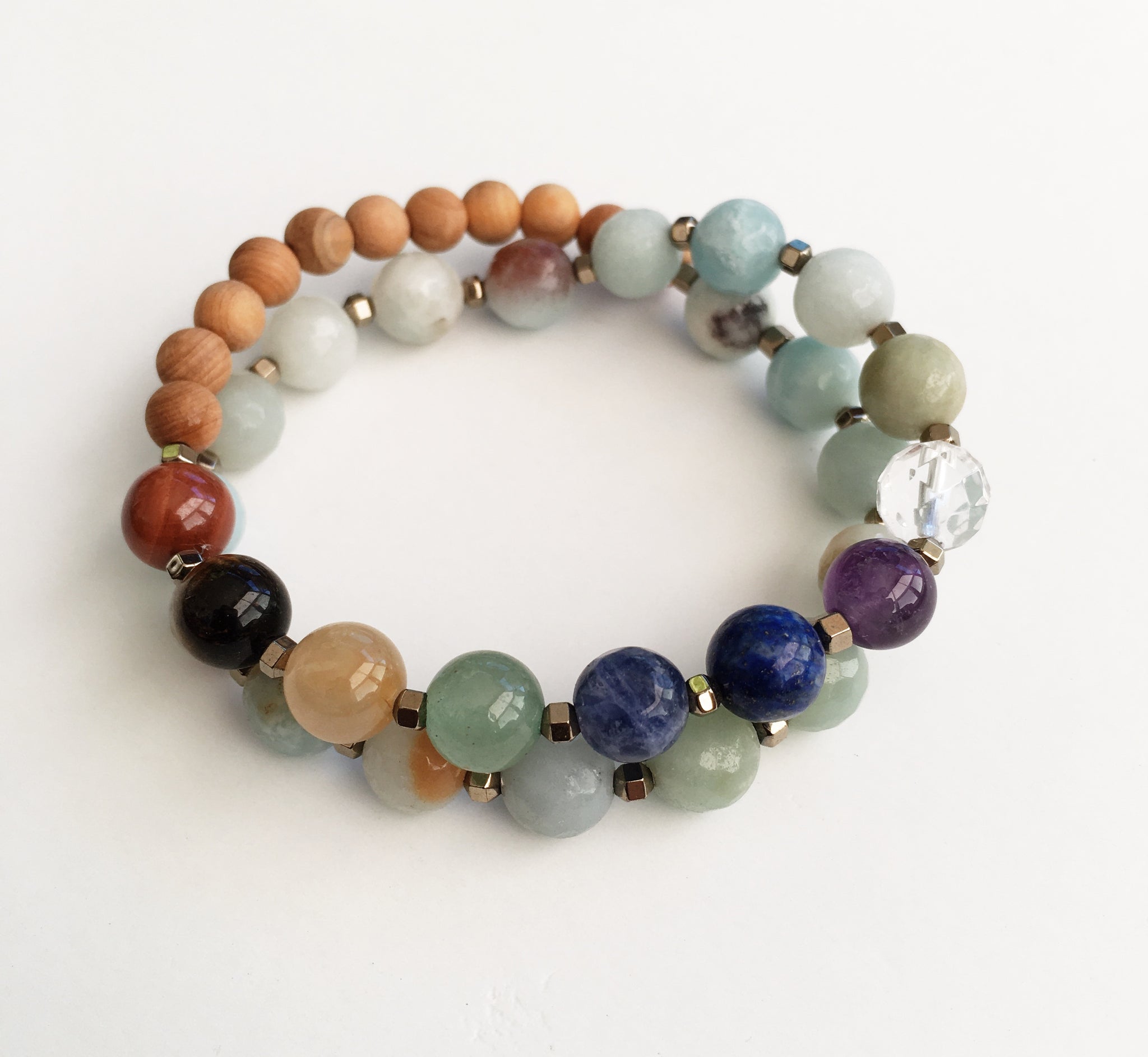 This double wrap stretchy mala bracelet contains 27, 8 mm gemstones & sandalwood beads. Of which are 7 round smooth chakra gemstones, 1 round faceted clear crystal quartz gemstone, and 19 round faceted amazonite gemstones. Gemstones are separated by 2mm Hematite plated spacer beads. 6mm round smooth sandalwood beads are used to complete the quarter mala bracelet design.