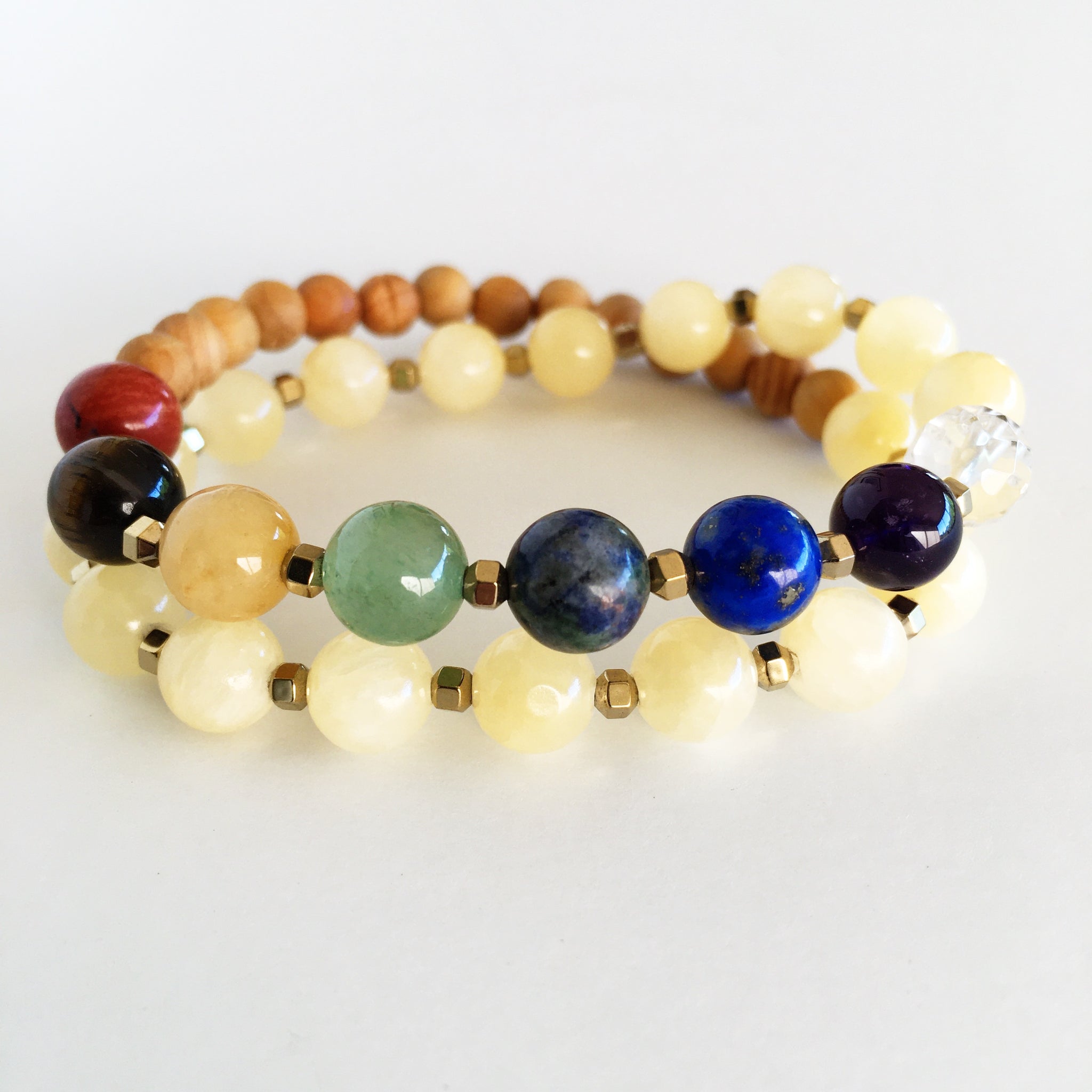 This double wrap stretchy mala bracelet contains 27, 8 mm gemstones & sandalwood beads. Of which are 7 round smooth chakra gemstones, 1 round faceted clear crystal quartz gemstone, and 19 round smooth natural yellow jade gemstones. Gemstones are separated by 2mm Hematite Hexagon spacer beads. 6mm sandalwood beads are used to complete to complete the design.