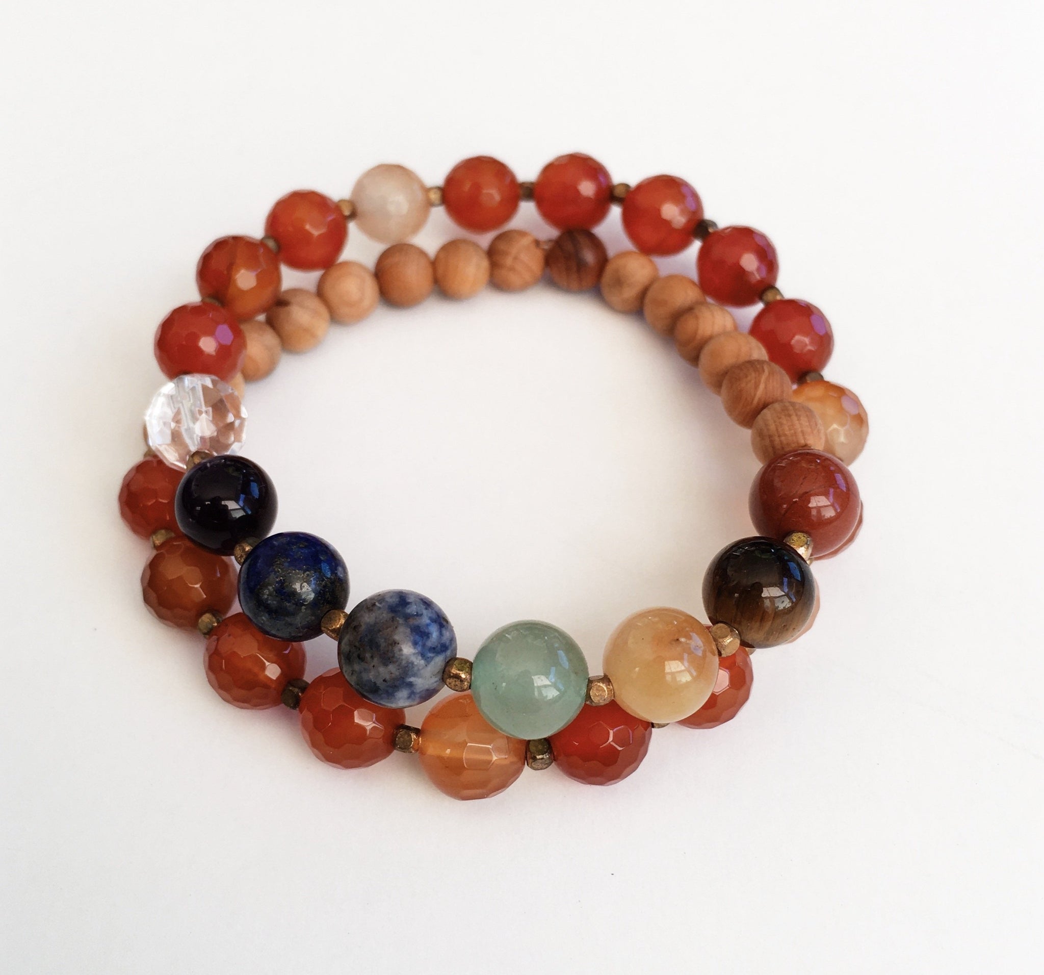 This double wrap stretchy mala bracelet contains 27, 8 mm gemstones & sandalwood beads. Of which are 7 round smooth chakra gemstones, 1 round faceted clear crystal quartz gemstone, and 19 round faceted carnelian gemstones. Gemstones are separated by 2mm German Silver brass-plated spacer beads. 6mm round smooth sandalwood beads are used to complete the quarter mala bracelet design.