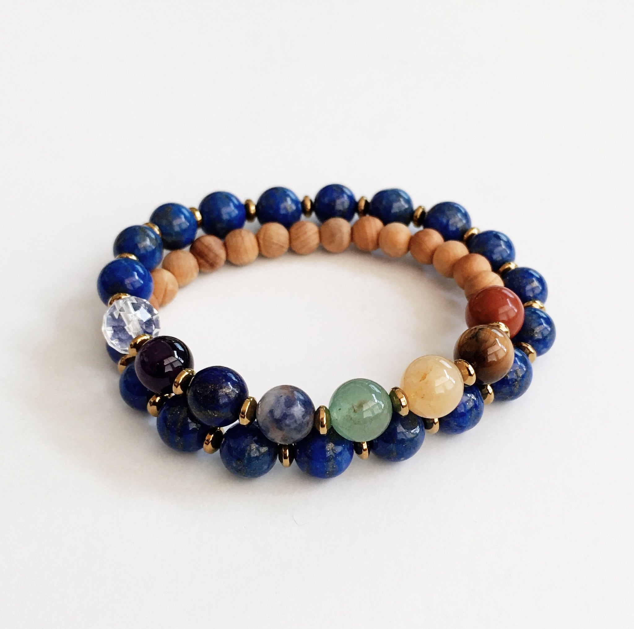 This double wrap stretchy mala bracelet contains 27, 8 mm gemstones & sandalwood beads. Of which are 7 round smooth chakra gemstones, 1 round faceted clear crystal quartz gemstone, and 19 round smooth lapis lazuli gemstones. Gemstones are separated by 2mm Hematite plated spacer beads. 6mm round smooth sandalwood beads are used to complete the quarter mala bracelet design.