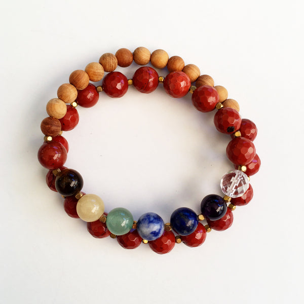 This double wrap stretchy mala bracelet contains 27, 8 mm gemstones & sandalwood beads. Of which are 7 round smooth chakra gemstones, 1 round faceted clear crystal quartz gemstone, and 19 round faceted red jasper gemstones. Gemstones are separated by 2mm German Silver brass plated spacer beads. 6mm round smooth sandalwood beads are used to complete the quarter mala bracelet design.